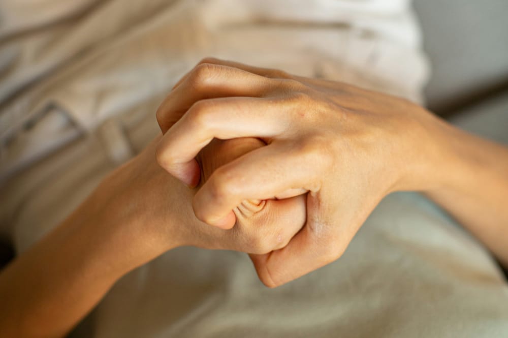 Two hands tightly clasped together, fingers interlocked and gripping with visible tension — a visual metaphor for white-knuckling your way through the Christian life.