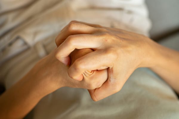 Two hands tightly clasped together, fingers interlocked and gripping with visible tension — a visual metaphor for white-knuckling your way through the Christian life.
